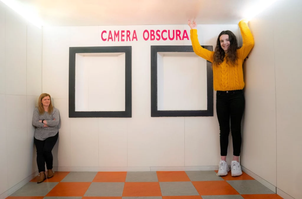 The Ames Room is a type of visual illusion that uses a distorted room to deceive the viewer.